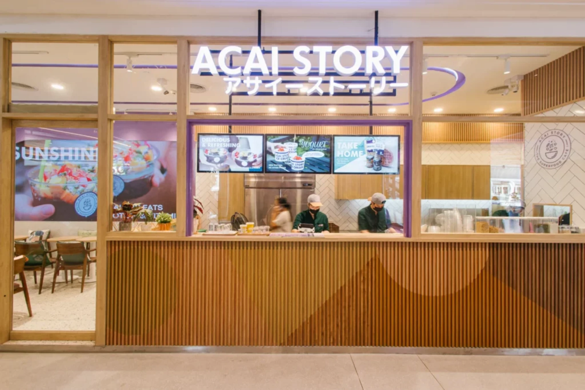 A stylish, modern cafe interior with a large, indoor tree and natural light of the ACAI STORY cafe at Gaysorn Village.